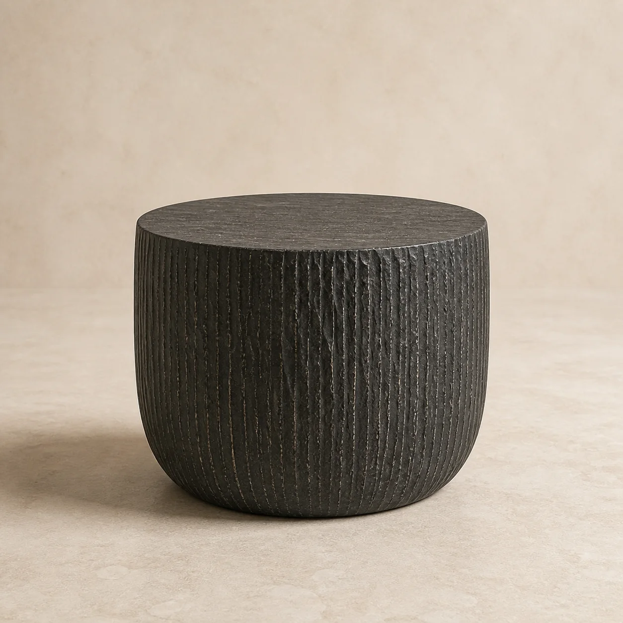 Ceniza Drum Table studio concept visual in charcoal volcanic stone, smooth honed top