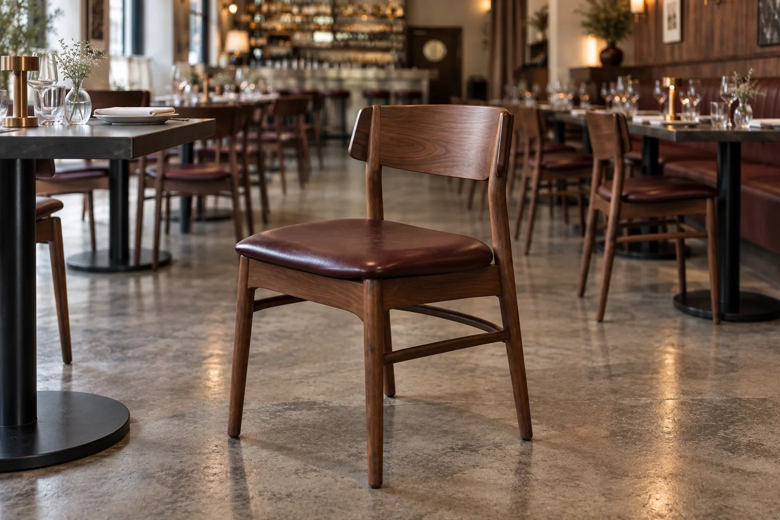 Close view of walnut restaurant chair with oxblood upholstery and curved timber back