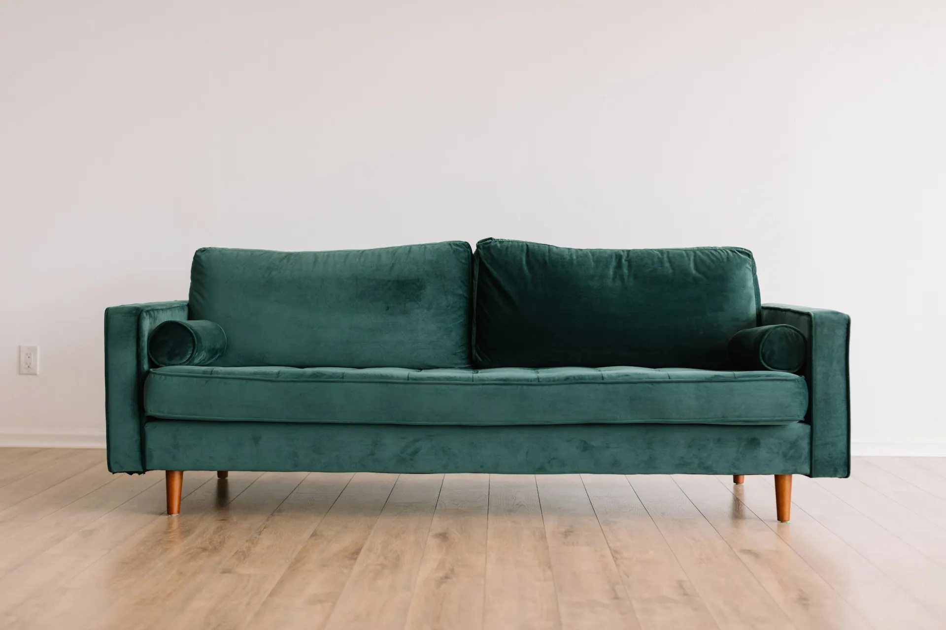 Tan leather sofa with black metal frame and beige cushion in a curtained showroom