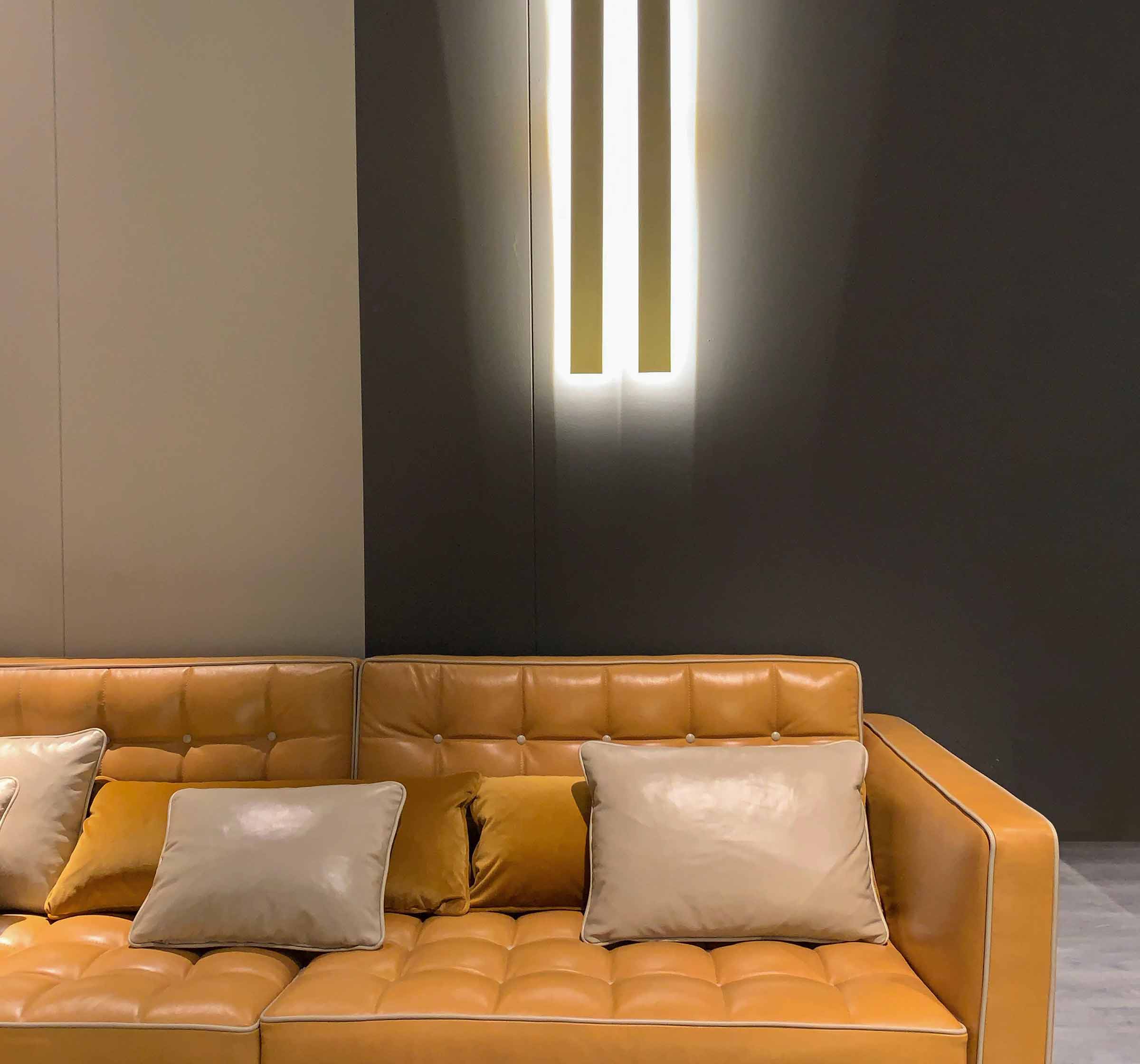 Green velvet three-seater sofa with bolster cushions on a hardwood floor