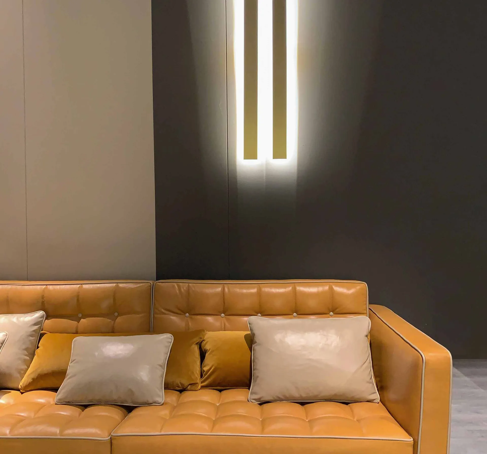Green velvet three-seater sofa with bolster cushions on a hardwood floor