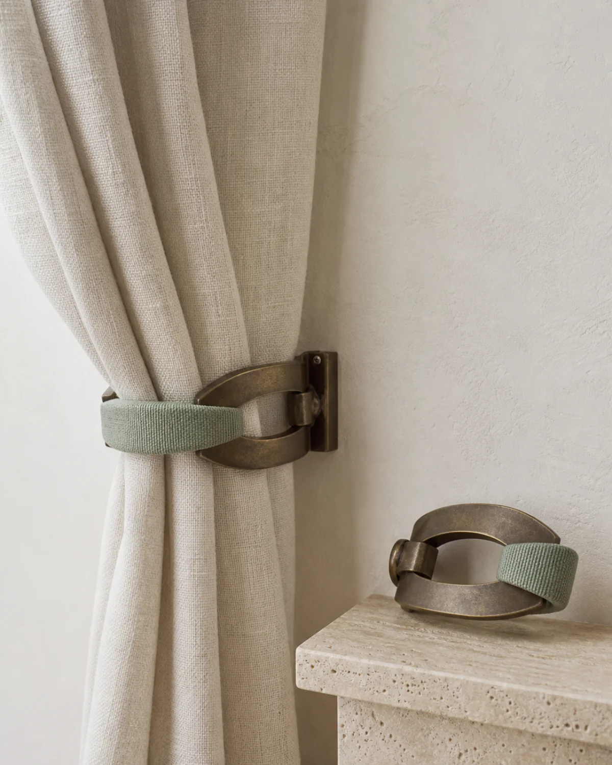 Celadon Crest sculptural wall-mounted curtain holdback set in antique bronze with woven celadon detail